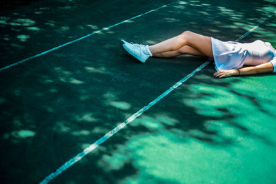 Low section of young woman lying on tennis court