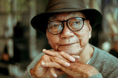 Close-up of thoughtful senior man with hands clasped sitting in cafe