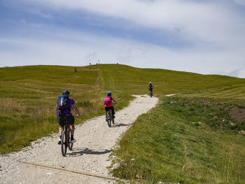 Rear view of people riding bicycles on mountain