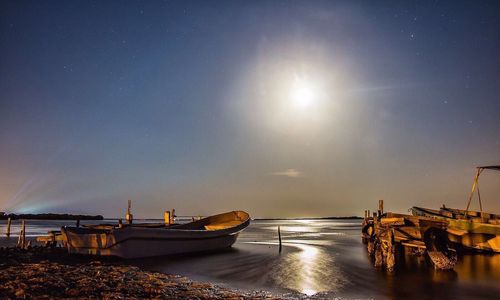 Boats moored in sea against clear sky at sunset