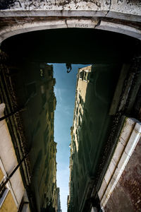 Low angle view of bridge over canal amidst buildings in city