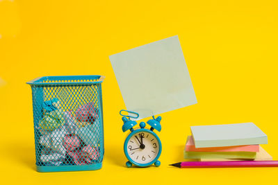 Close-up of clock on table against yellow background