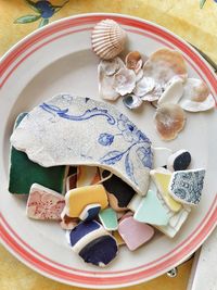 High angle view of shells and colorful ceramics in plate on table