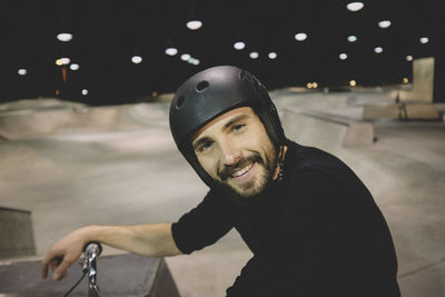 Portrait of smiling man with bicycle at skateboard park