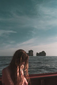 Woman by railing of boat on sea against sky