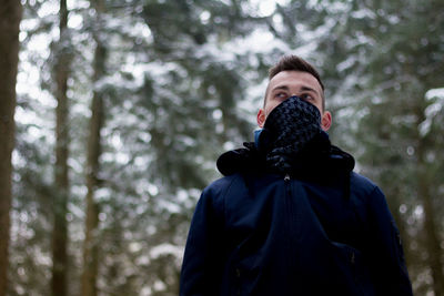 Young man standing against trees during winter