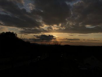 Silhouette landscape against dramatic sky during sunset