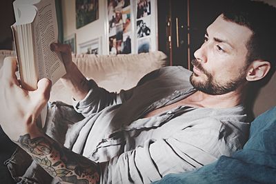 Man reading book on sofa at home