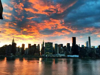 Cityscape by river against sky