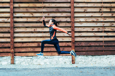 Full length of young man jumping against wall