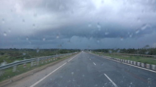 Country road against cloudy sky