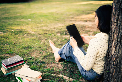 Side view of woman reading book in field