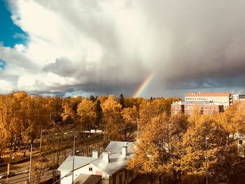 Rainbow over houses against sky during autumn