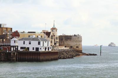 Buildings by sea against sky