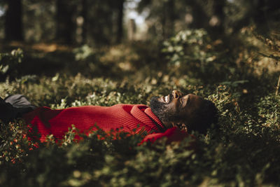 Smiling man resting while lying down in forest during vacation