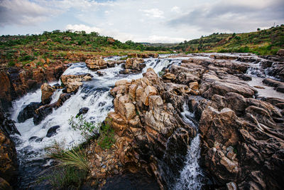 Scenic view of waterfall against sky