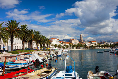 Boats moored by buildings in city against sky