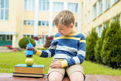 Boy looking away while sitting outdoors