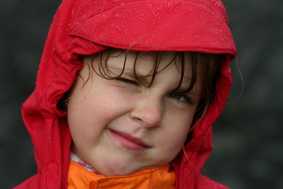 Close-up portrait of girl wearing raincoat winking eye
