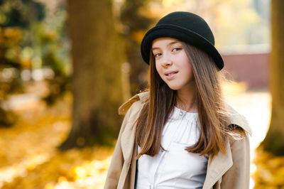 Portrait of beautiful young woman standing against blurred background