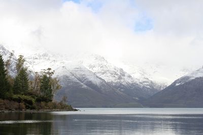 Scenic view of lake and snowcapped mountains against cloudy sky