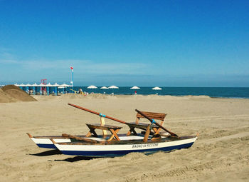 Sailboat on beach against blue sky