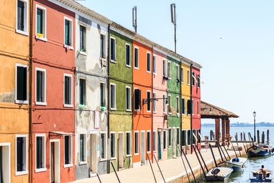 Buildings by canal against clear sky