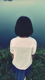 Rear view of girl standing by lake