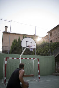 Man playing basketball hoop against sky