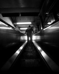 Rear view of man standing on escalator