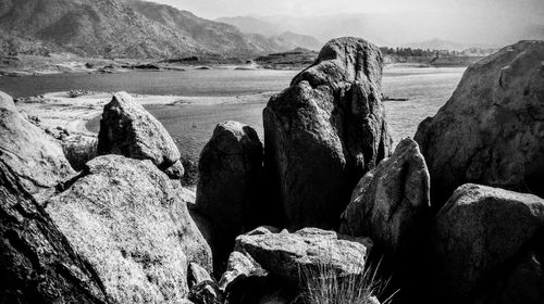 Rocks on shore by sea against sky