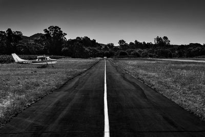 Biplane by runway against clear sky