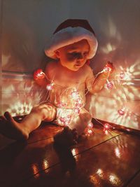 Close-up of cute baby with illuminated lights on floor at home