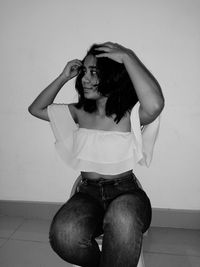 Young woman standing against wall at home