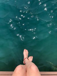 Low section of woman sitting on pier over sea