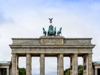 Low angle view of triumphal arch against cloudy sky