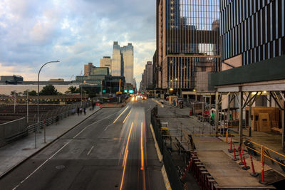 Vehicles on road amidst buildings in city against sky