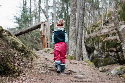 Rear view of a young girl hiking through a forest in sweden