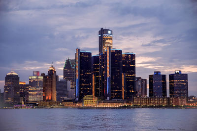 View of city at waterfront against cloudy sky