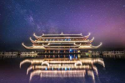 Digital composite image of illuminated building against sky at night