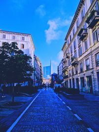 Street amidst trees against blue sky