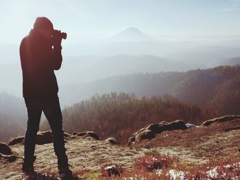 Professional photographer takes photos with mirror camera on peak of rock. professional photographer