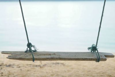 Close-up of rope tied to wooden post in sea against sky