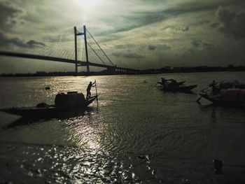 Silhouette bridge over sea against sky