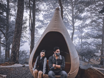 Young couple sitting in snow covered forest