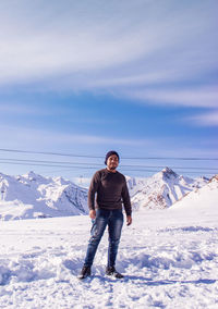 Portrait of smiling man standing on snowcapped mountain against sky