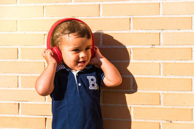 Happy boy standing against brick wall