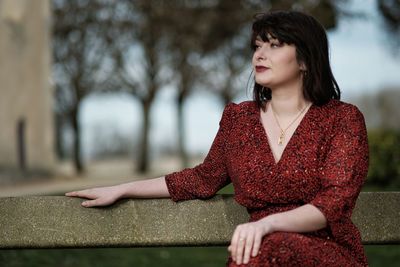 Young woman looking away while sitting outdoors