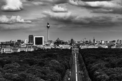 Tower amidst buildings in city against cloudy sky