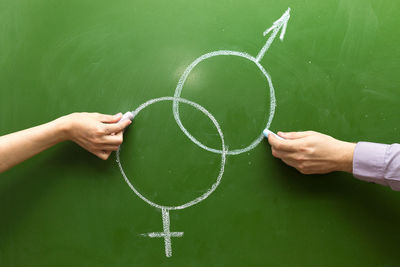 Male and female hands draw symbols of masculine feminine principle with chalk on the blackboard. 